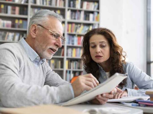 Anziano che aiuta una giovane donna nello studio