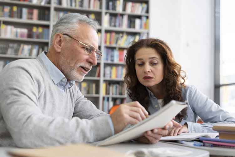 Anziano che aiuta una giovane donna nello studio